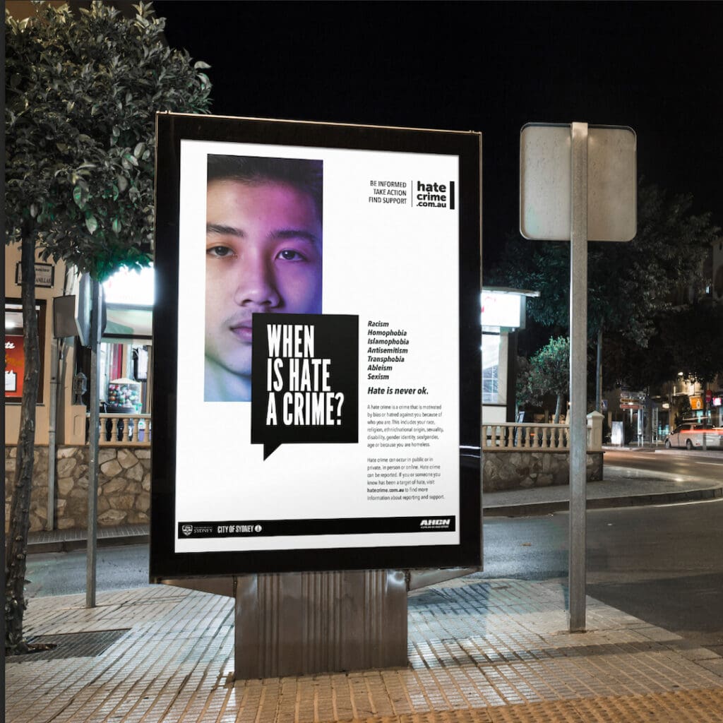 Public service announcement Adshell billboard on a city street at night asking ‘WHEN IS HATE A CRIME?’ with a website ‘hatecrime.com.au’ for information and support, highlighting case studies.